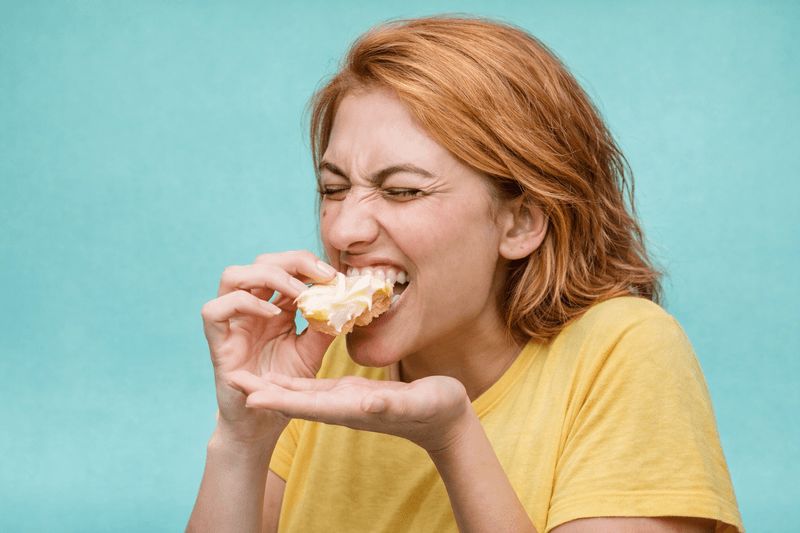 Mujer masticando pan con queso crema, esfuerzo y coordinación bucal