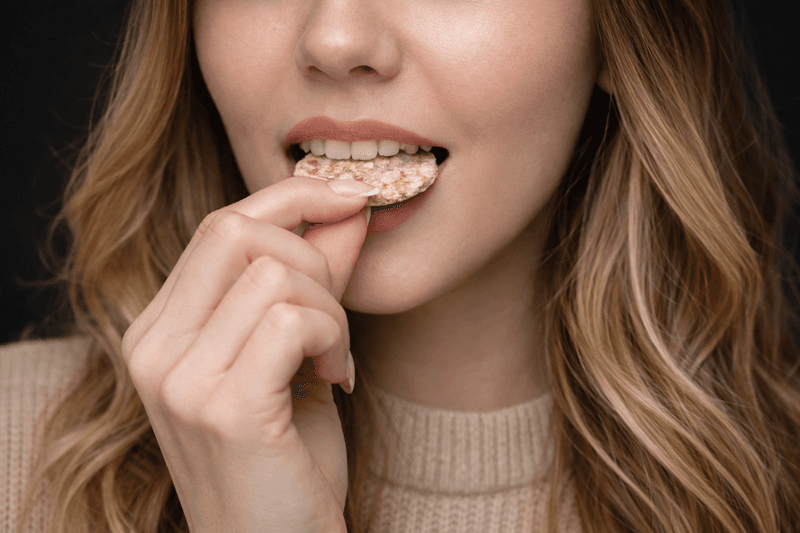 Mujer mordiendo una torta de arroz, fase de masticación y alimentación