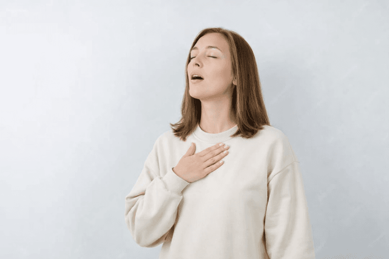 Mujer en respiración profunda y calma, mano en el pecho y control del aire